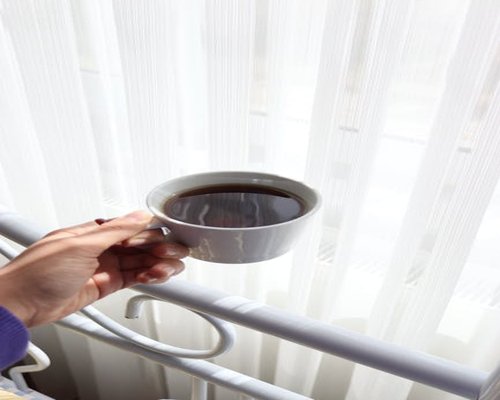 Person holding a warm coffee cup by the window in the morning